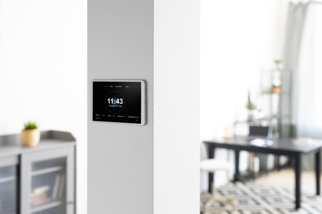 Homeowner using wall-mounted smart home tablet to adjust thermostat settings